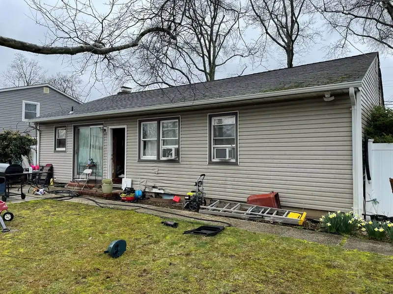 Back of a ranch with a ladder on the lawn, Amityville, NY